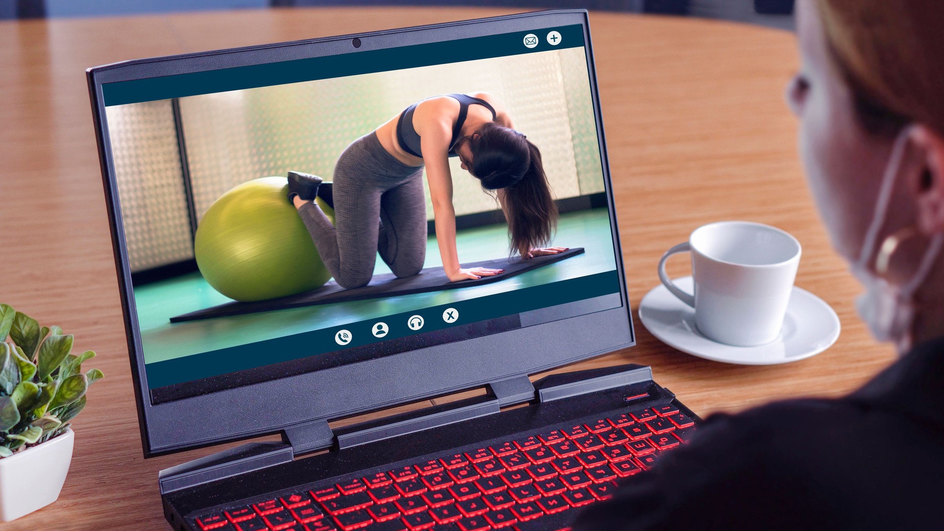 Rear view shot, blonde woman watching live video streaming online sport teach yoga with Pilates ball , staying from home self-isolation concept.